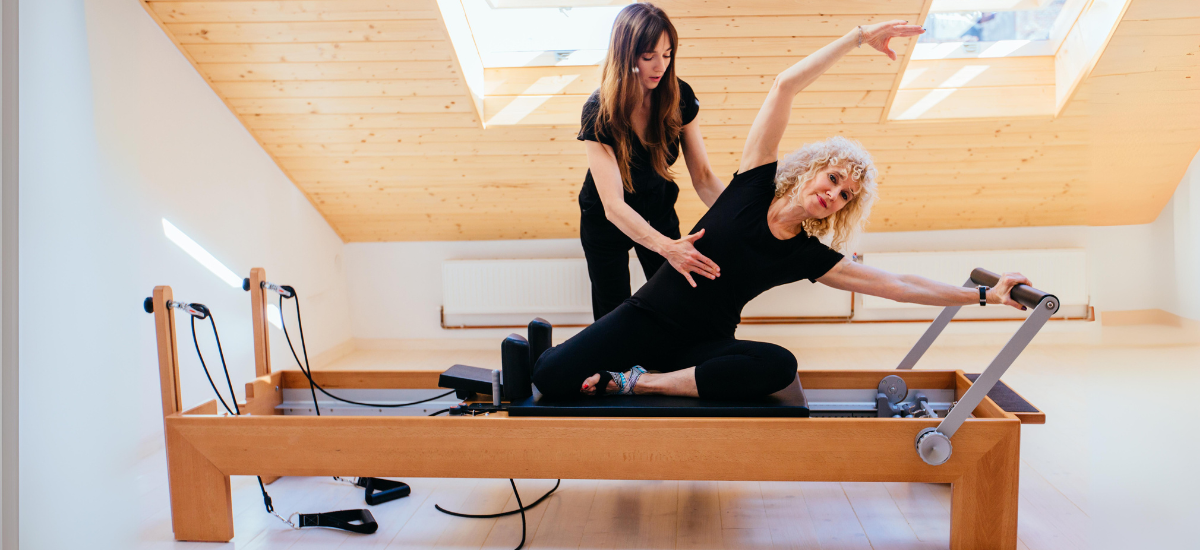 older woman doing pilates with instructor